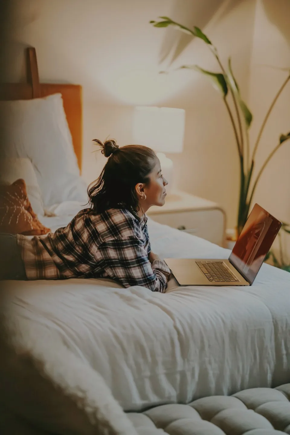 Femme allongée sur son lit, en train de composer un calendrier sur son ordinateur portable.